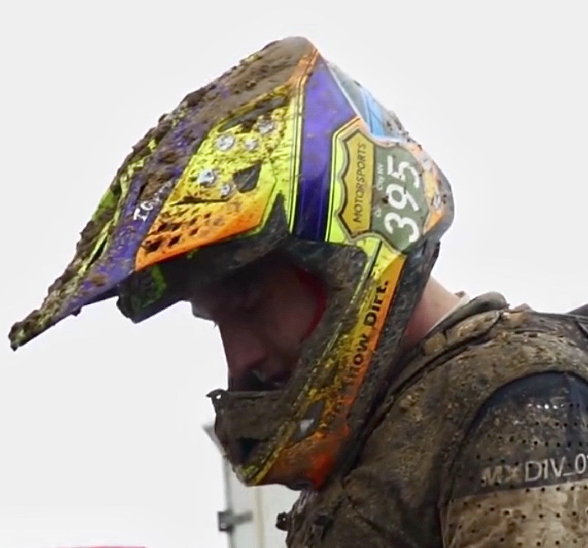 Man covered in mud wearing a motorcycle helmet
